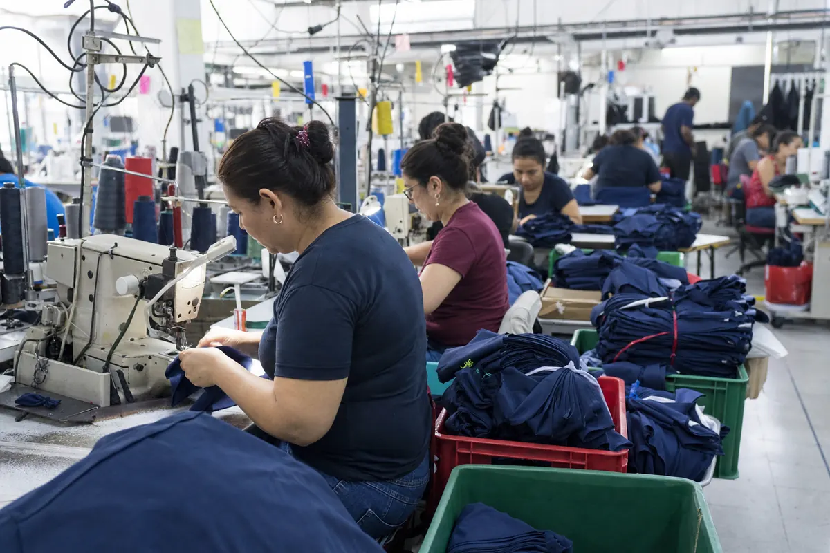 Operators sew t-shirts on lockstitch and overlock machines in a garment factory