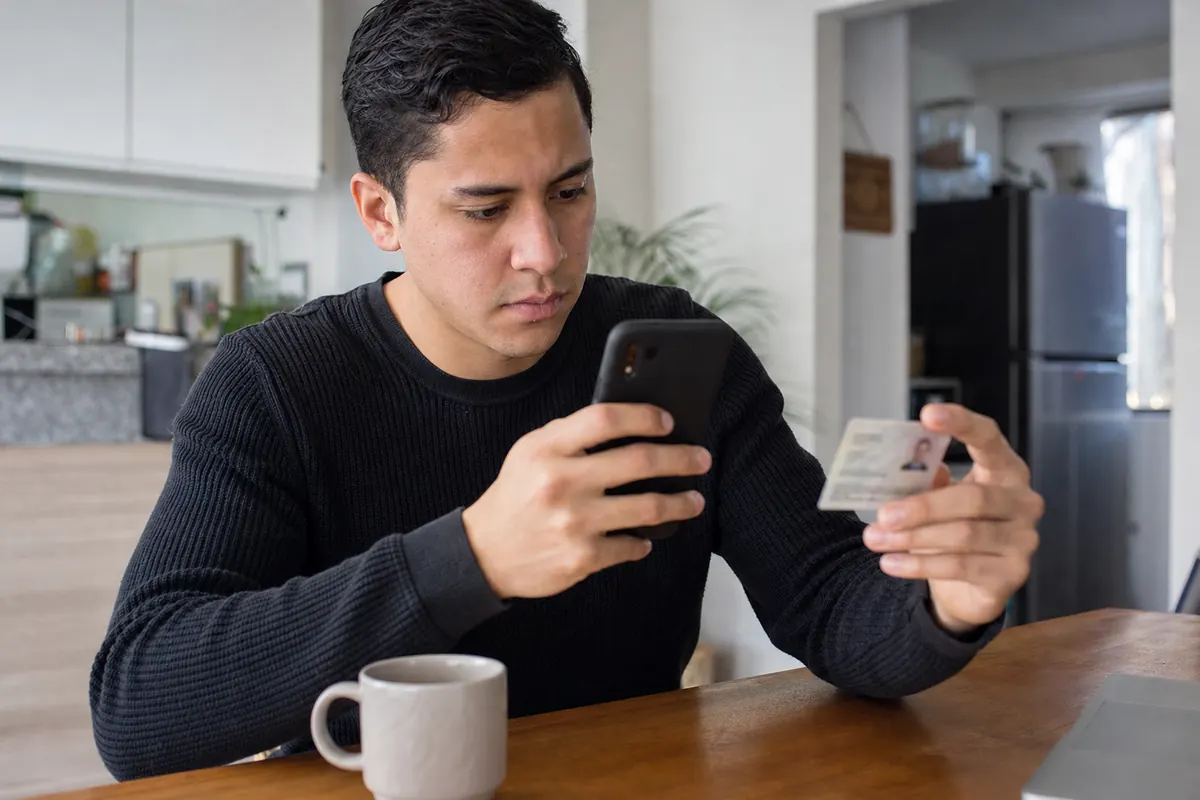 Young man photographs his ID card with his phone to complete an online loan application