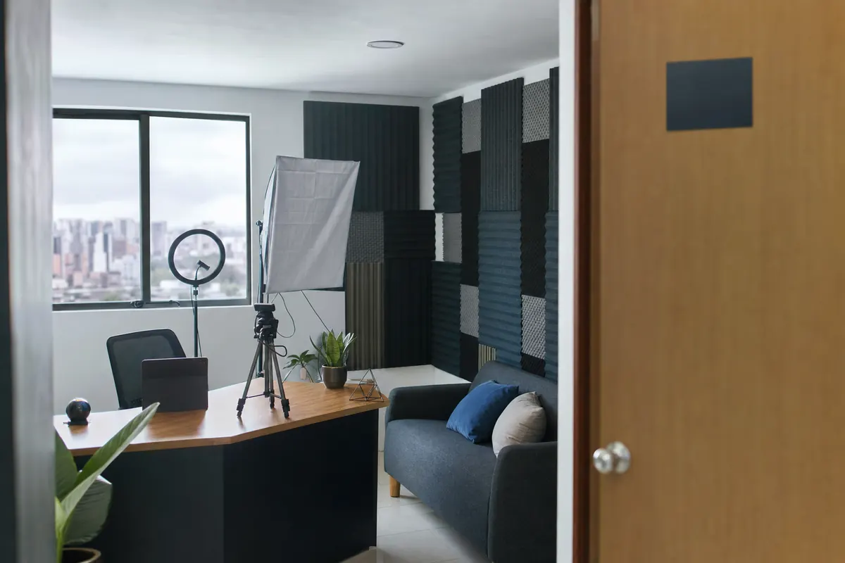 Empty, tidy streaming room with a ring light, a camera on a tripod and a sofa